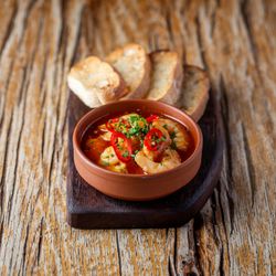 Shrimp in tomato sauce with sliced bread served on a wooden board
