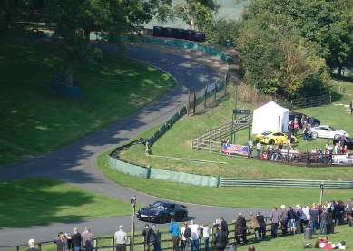 Car racing on a curved track with spectators watching from the side
