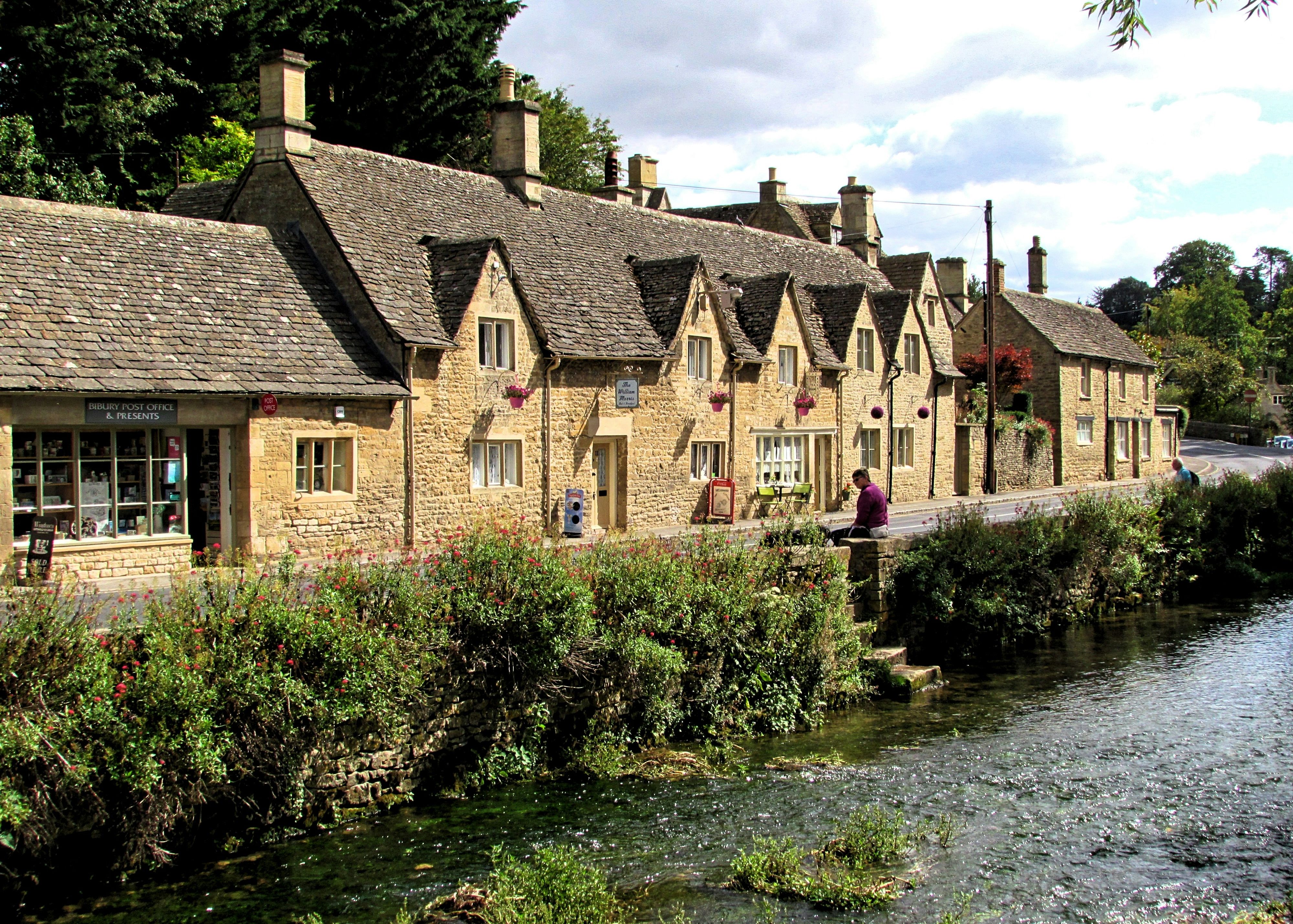 Row of traditional stone cottages beside a small river in an English village.