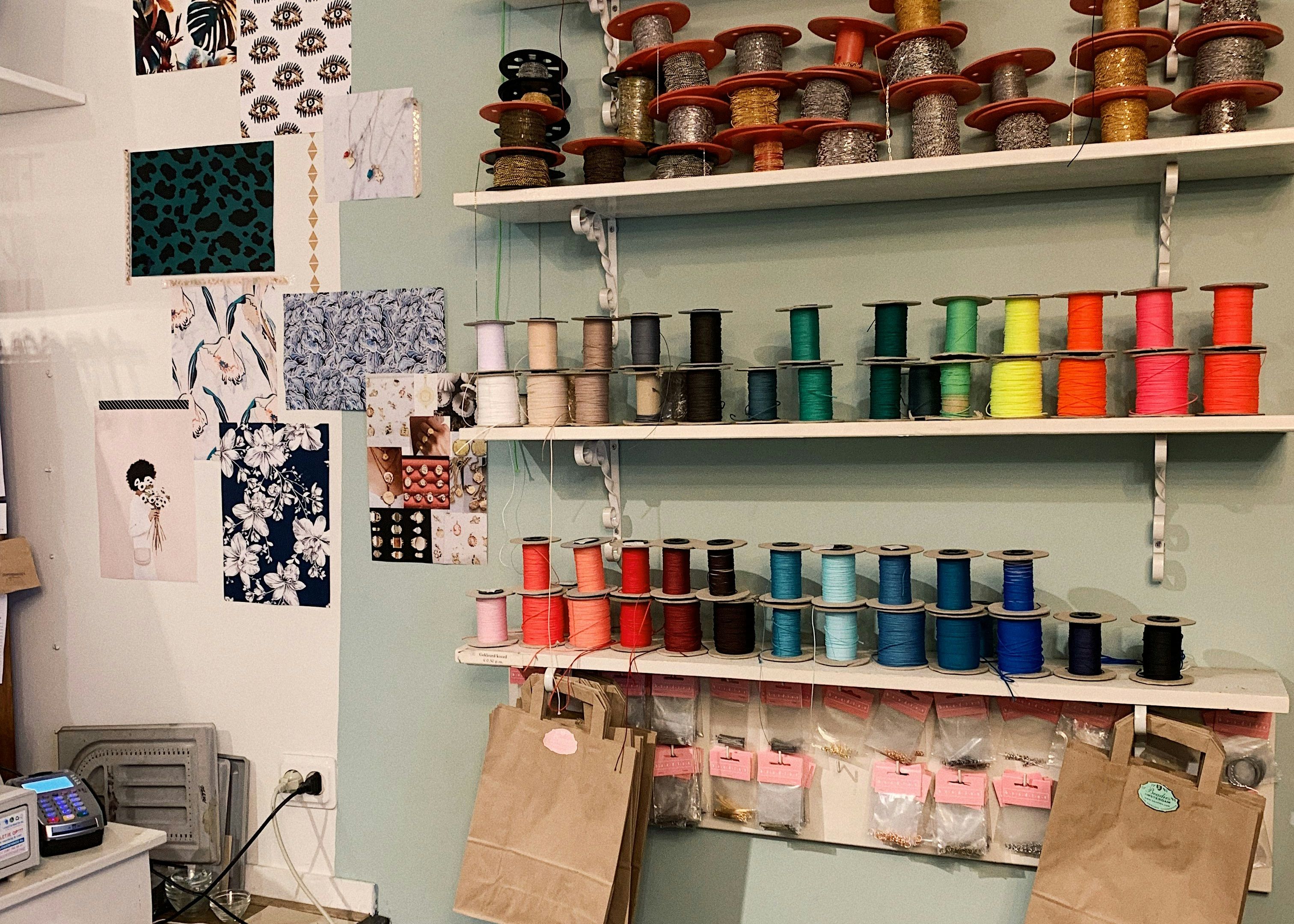 Wall shelves with colorful spools of thread and paper bags in a craft or sewing shop