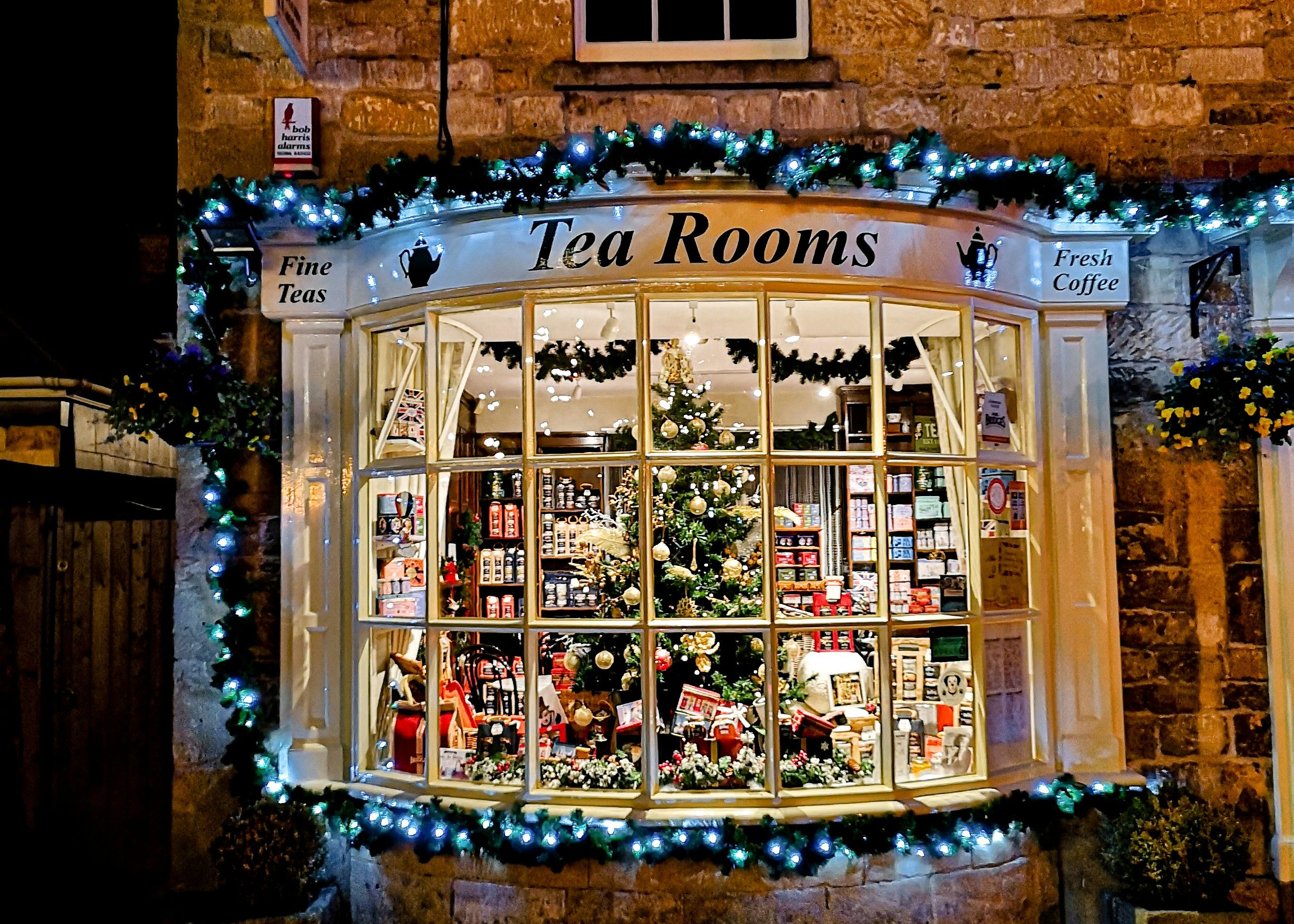 A warmly lit tea room decorated for Christmas with a festive window display and garlands of lights.