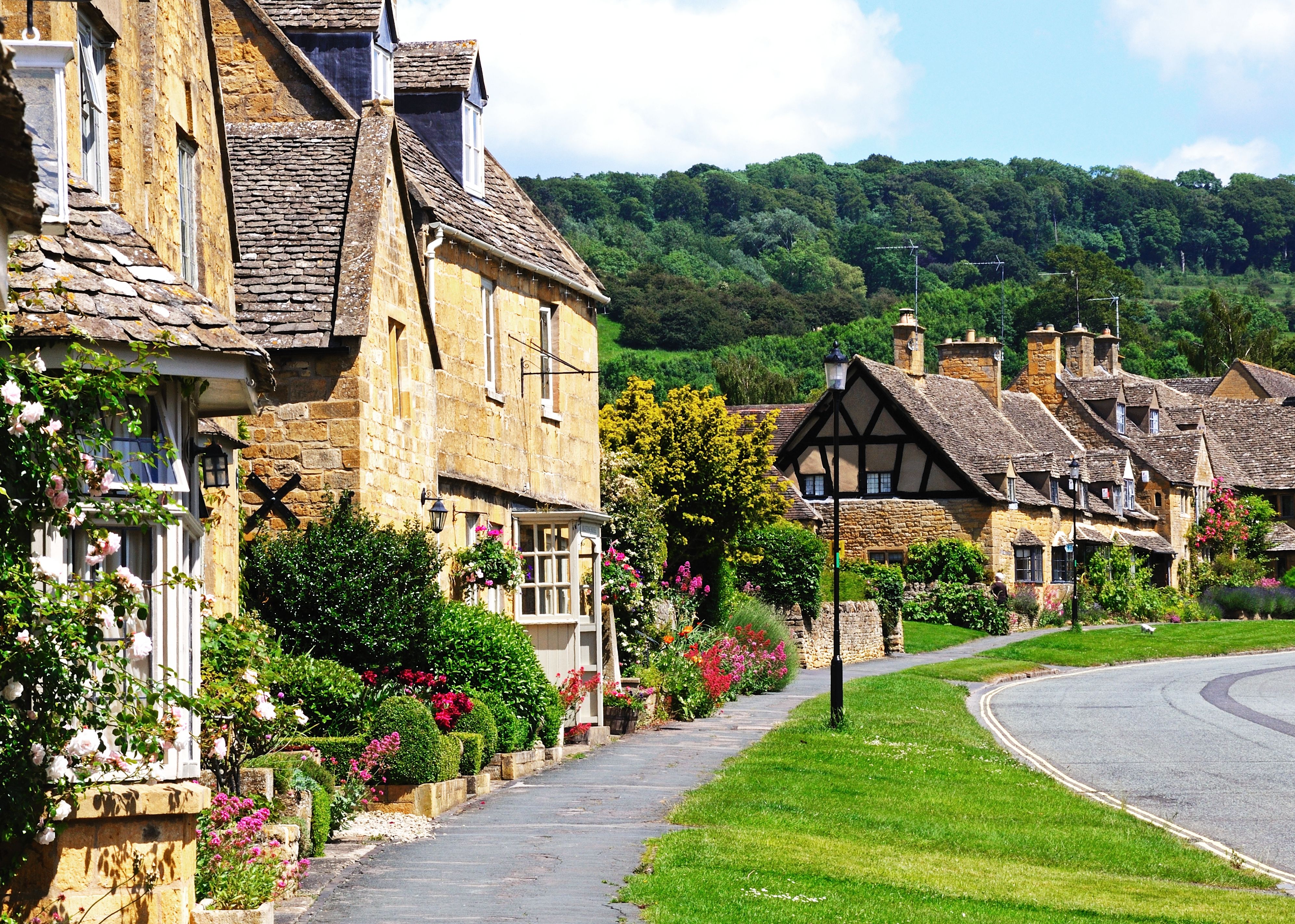 Quaint stone cottages in an English village with blooming gardens and greenery