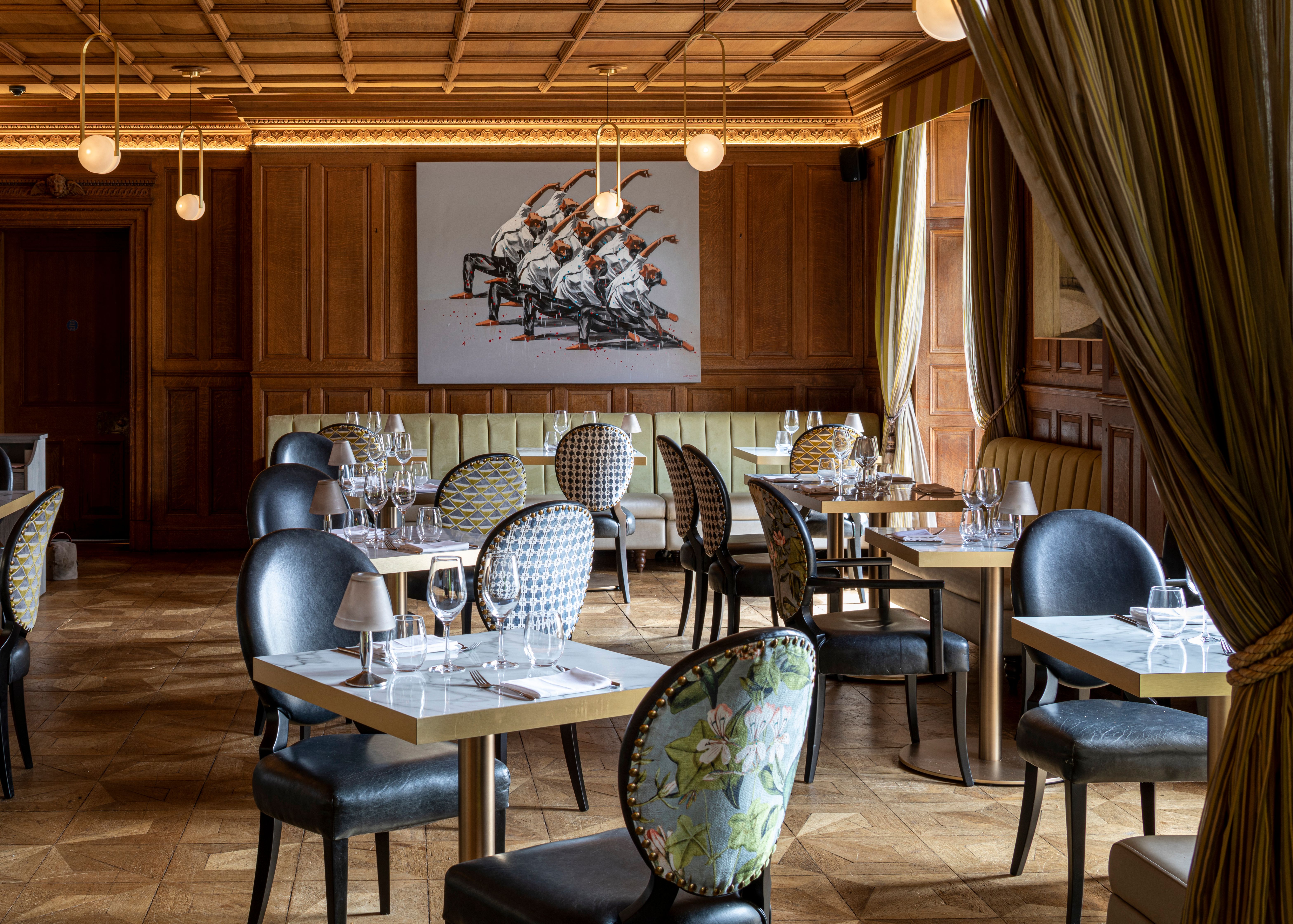 Elegant restaurant interior with patterned chairs, set tables, wooden paneling, and modern artwork on the wall.
