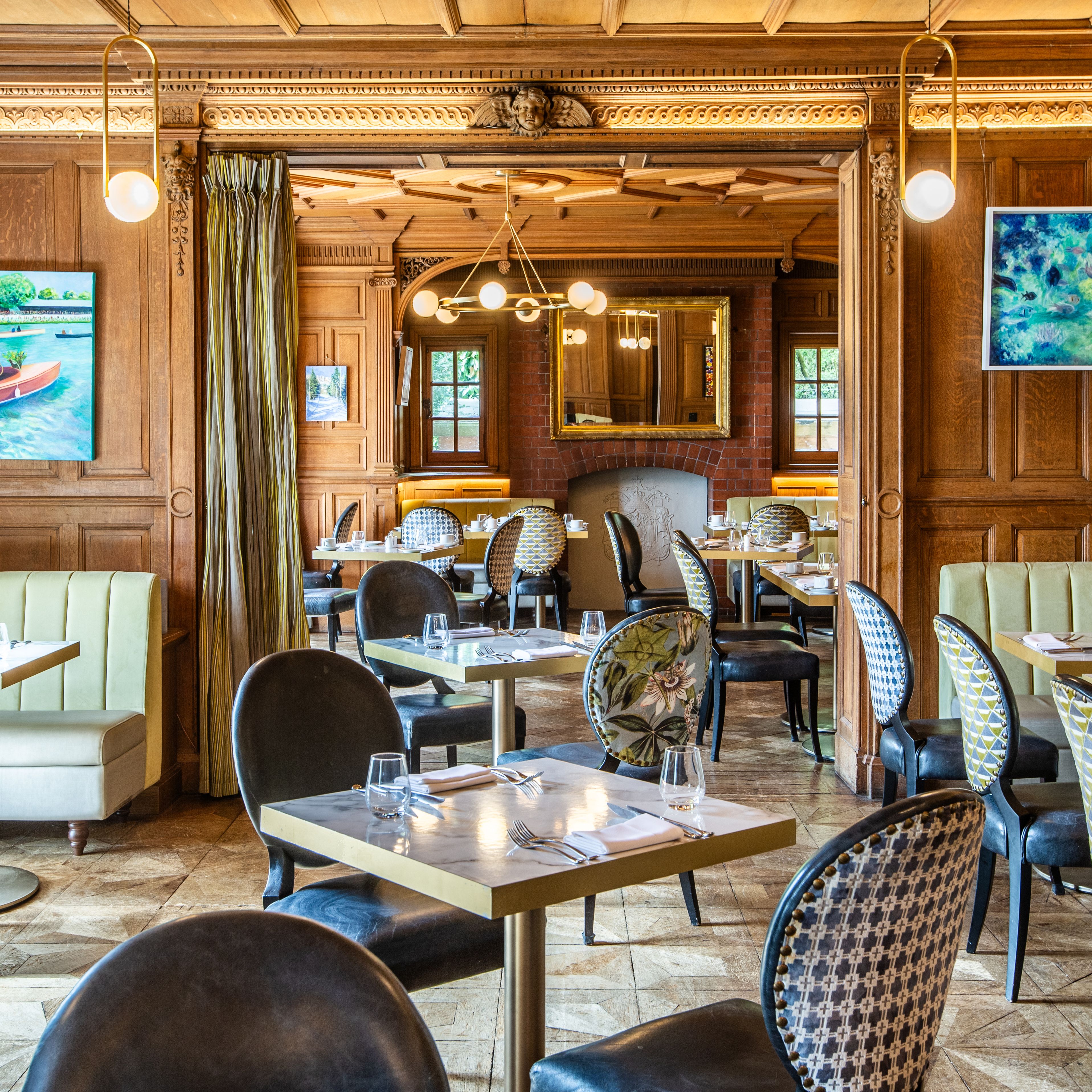 Elegant restaurant interior with wood paneling, cushioned seating, decorative chairs, and framed artwork on the walls.
