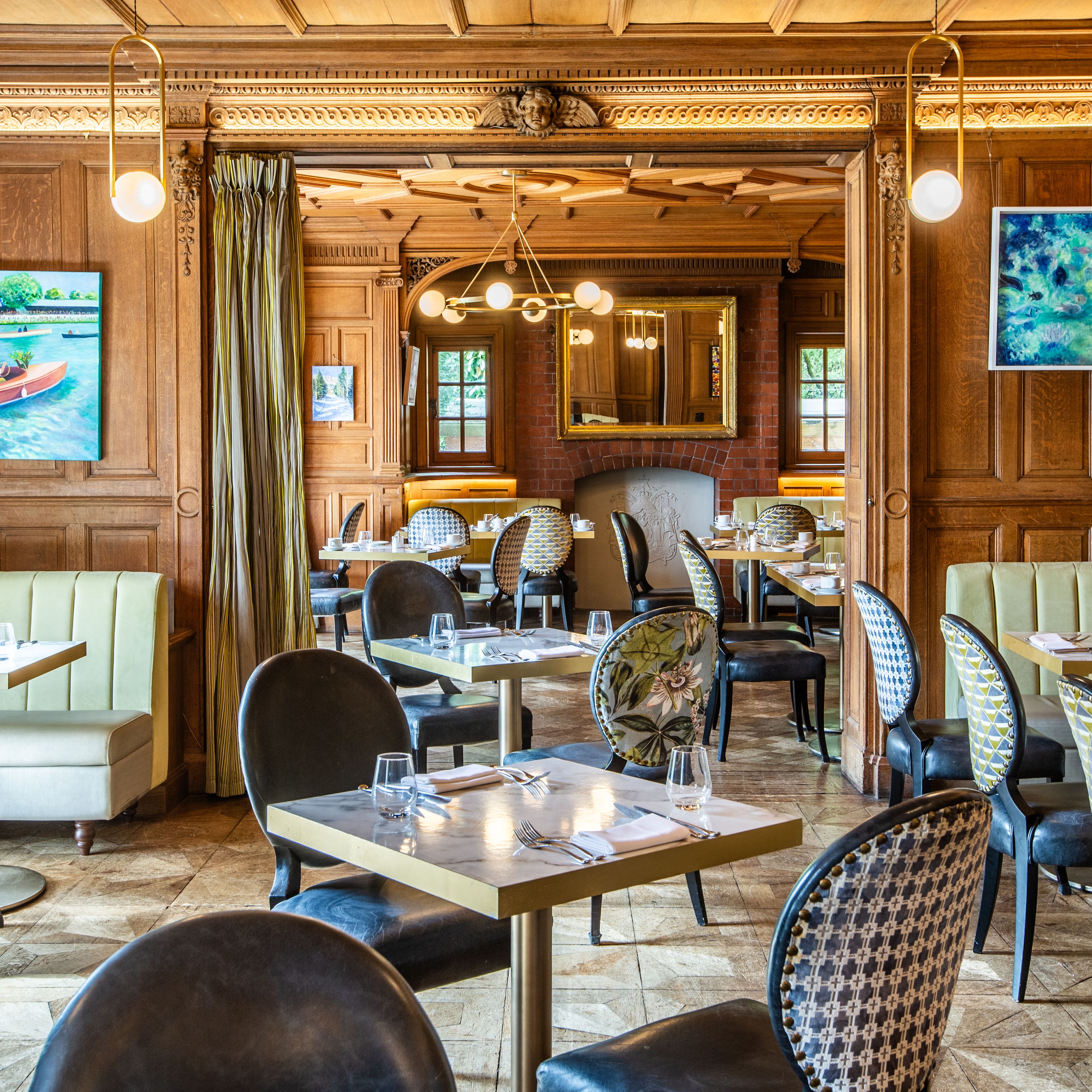 Elegant restaurant interior with wood paneling, cushioned seating, decorative chairs, and framed artwork on the walls.