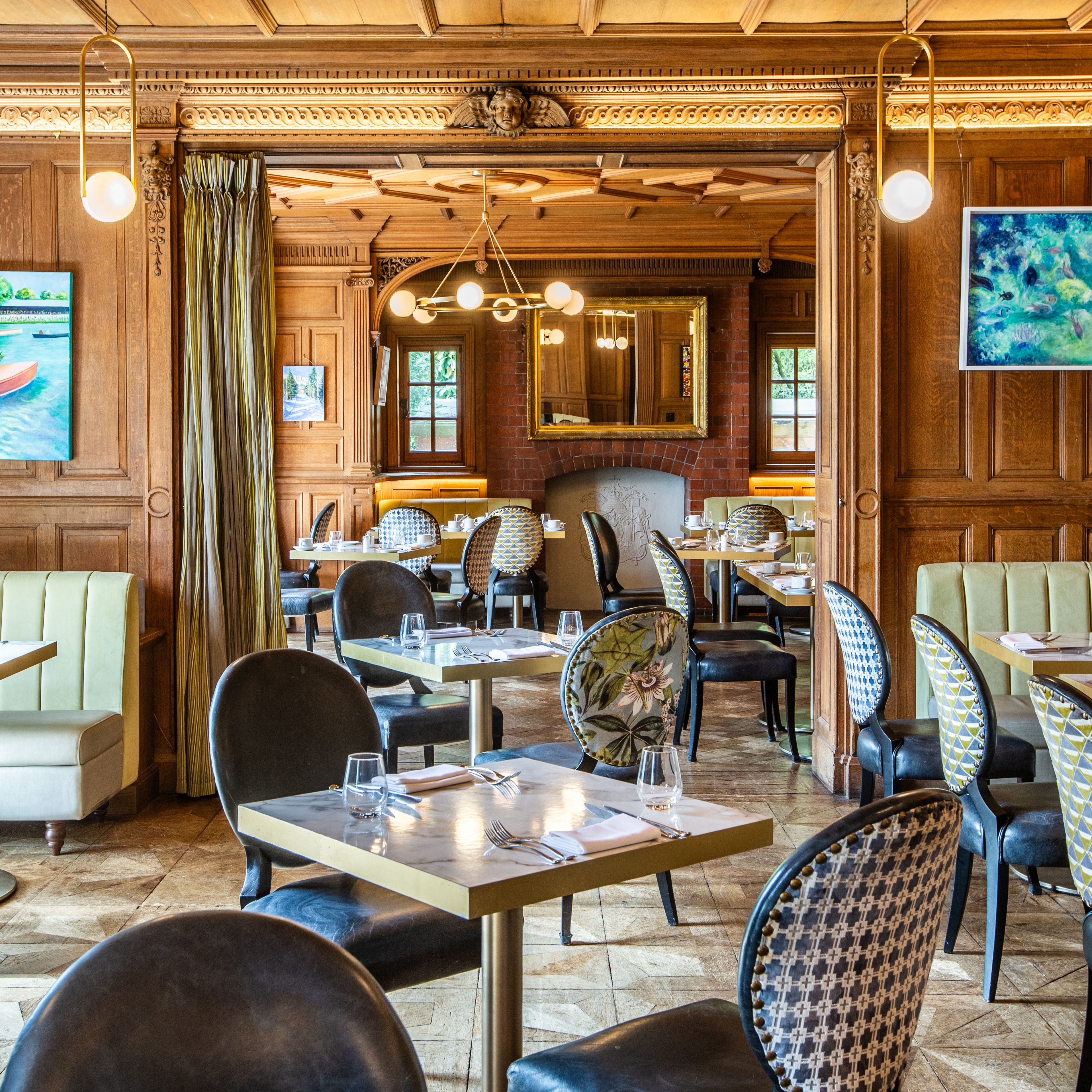 Elegant restaurant interior with wood paneling, cushioned seating, decorative chairs, and framed artwork on the walls.
