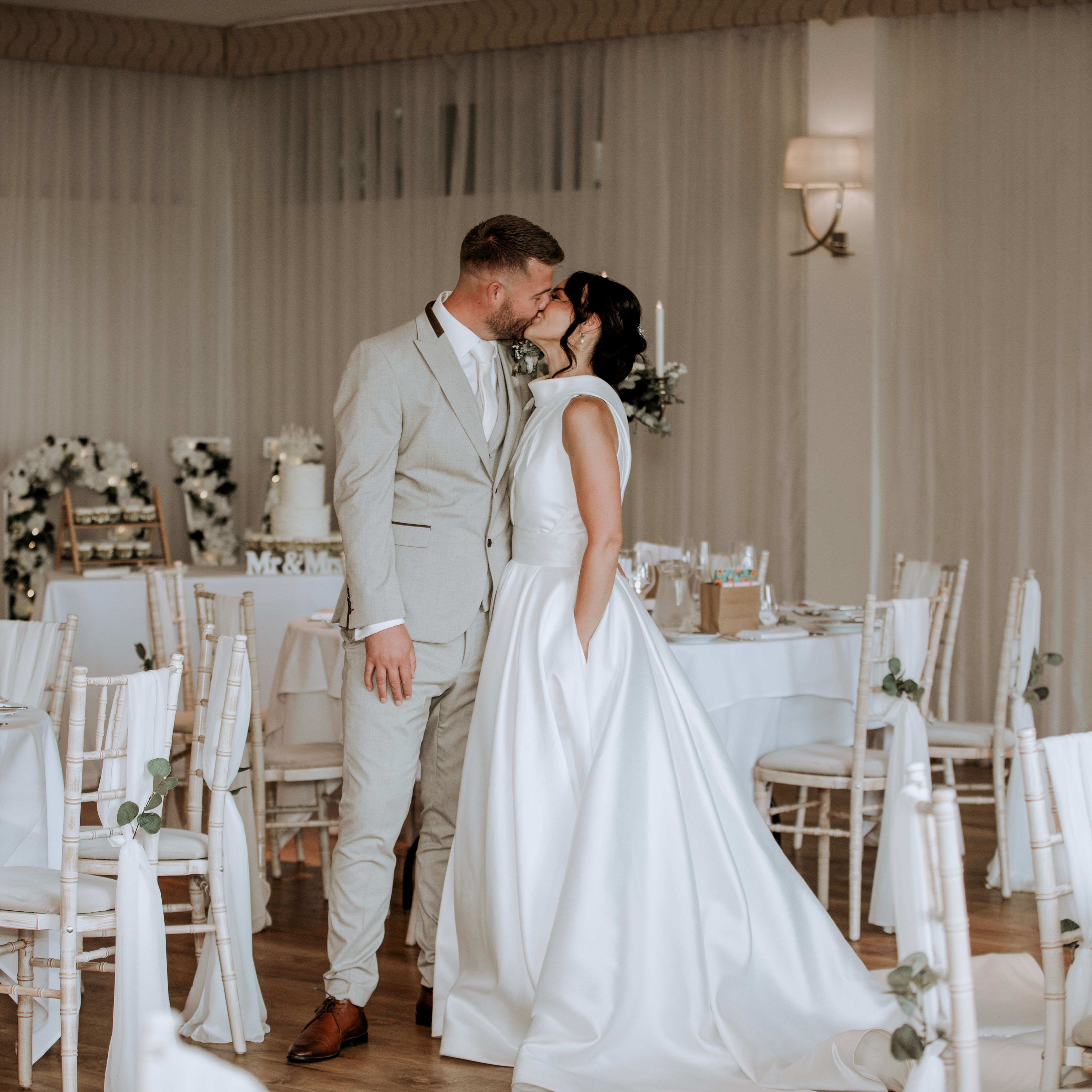 Bride and groom sharing a kiss in an elegantly decorated wedding reception venue.