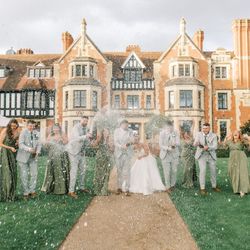 Wedding party celebrating with champagne in front of a large historic manor house