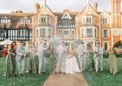 Wedding party celebrating with champagne in front of a large historic manor house