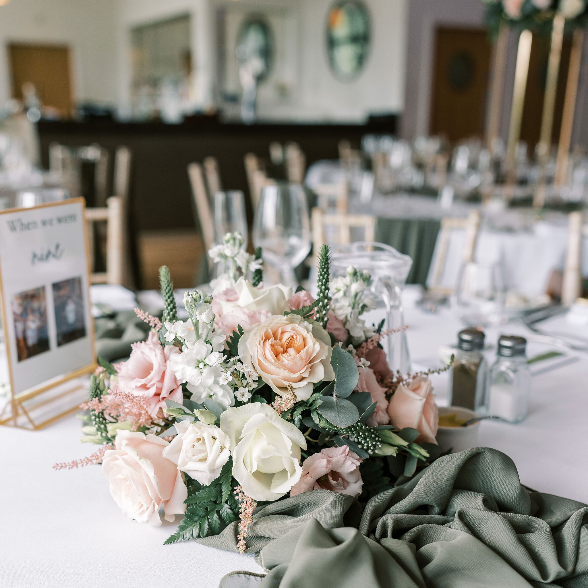 Elegant wedding table decorated with pastel flower arrangement, green table runner, and personalized coloring book for Chloe and Sean.