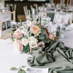 Elegant wedding table decorated with pastel flower arrangement, green table runner, and personalized coloring book for Chloe and Sean.