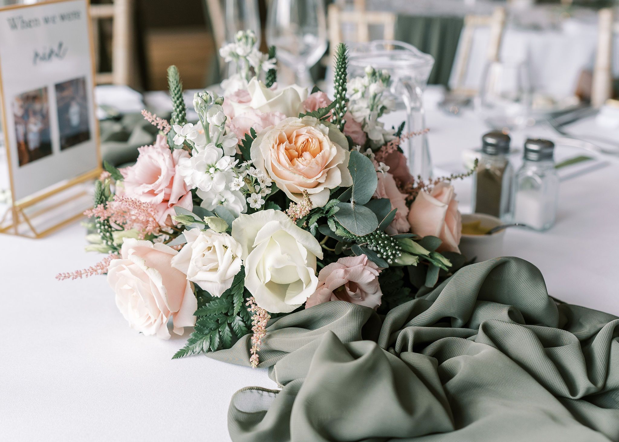 Elegant wedding table decorated with pastel flower arrangement, green table runner, and personalized coloring book for Chloe and Sean.
