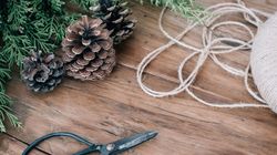 Pinecones, evergreen branches, twine, and scissors on a wooden table