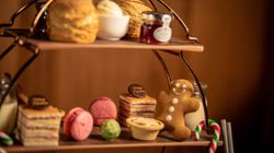 Festive afternoon tea stand with scones, clotted cream, jam, macarons, cakes, a gingerbread man, and candy canes.
