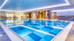 Modern indoor swimming pool with lounge chairs and safety equipment