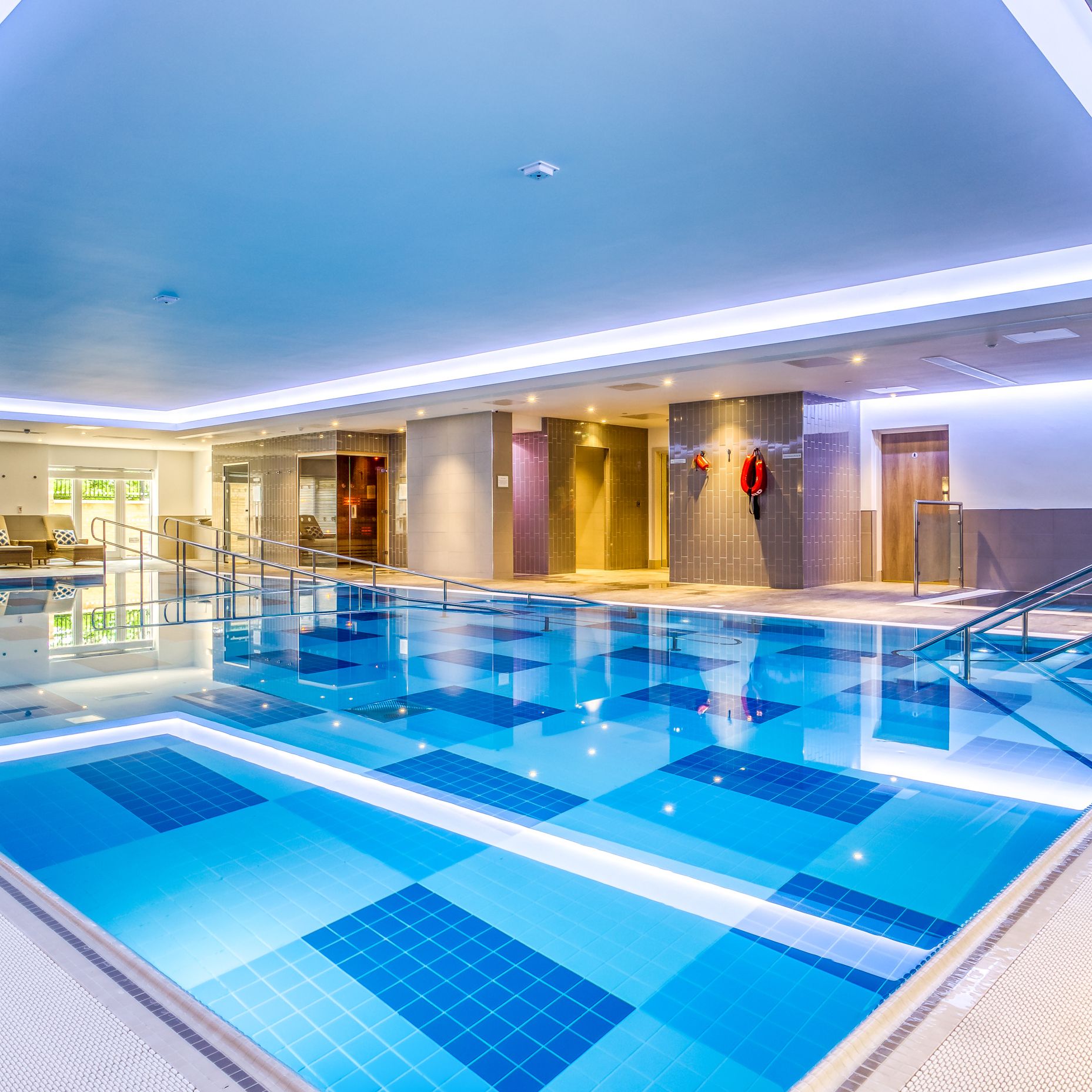 Modern indoor swimming pool with lounge chairs and safety equipment