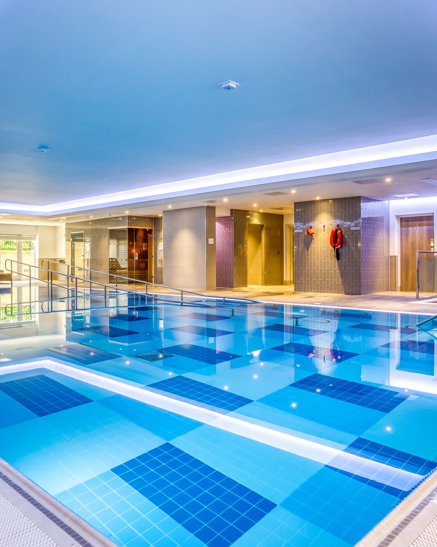Modern indoor swimming pool with lounge chairs and safety equipment