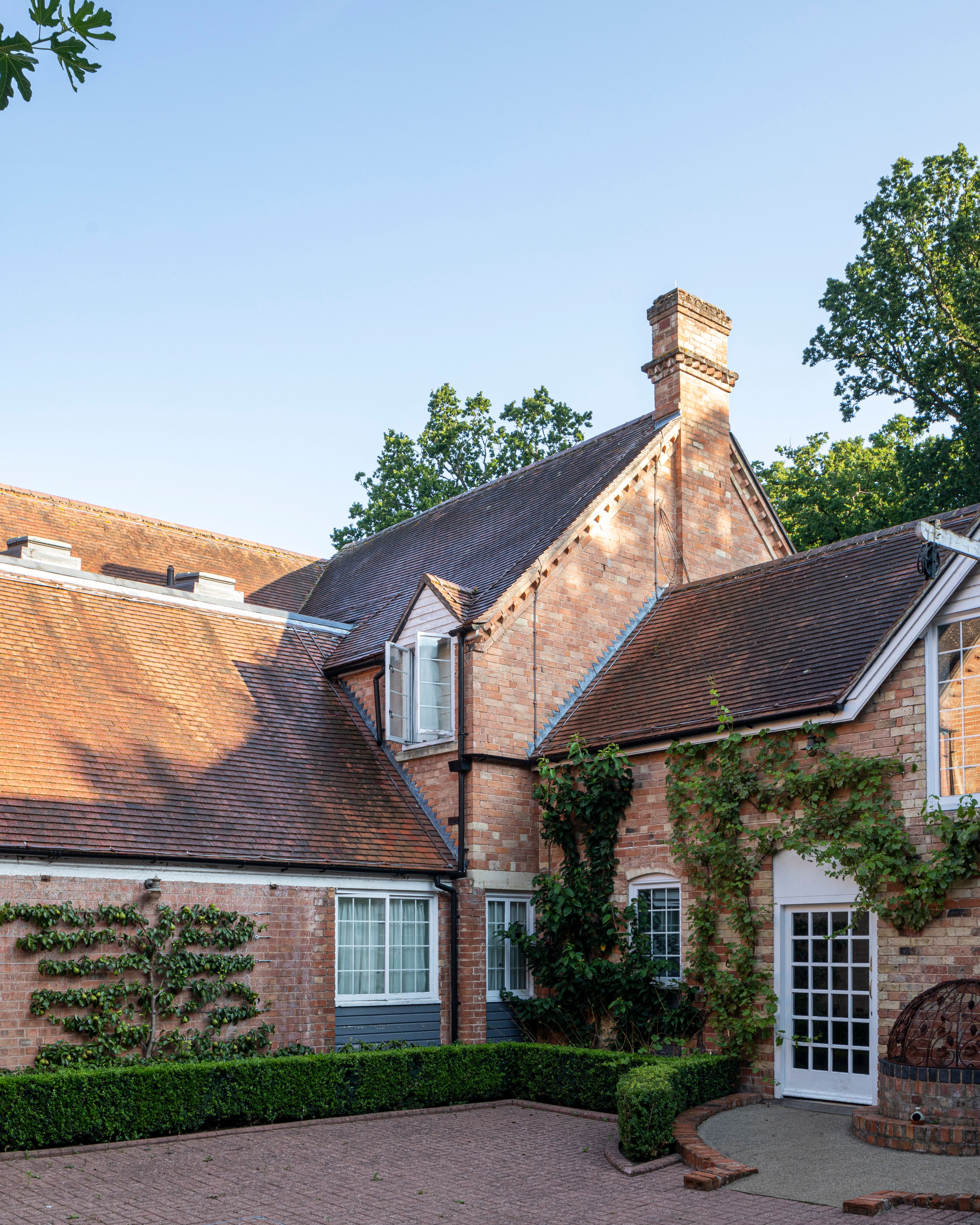 Traditional brick house with pitched roofs and climbing plants
