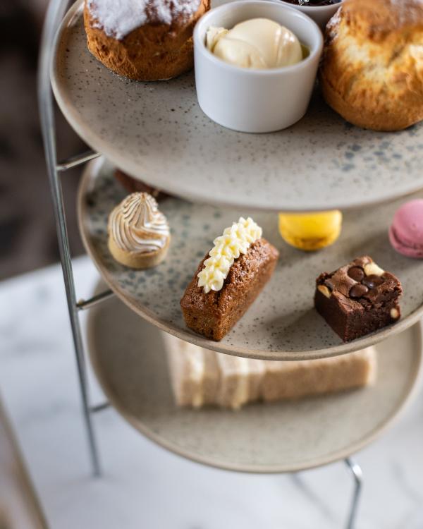 Three-tiered dessert stand with scones, cream, jam, small cakes and sweets
