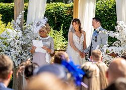 Couple getting married with beautiful flowers under the pergola in the gardens